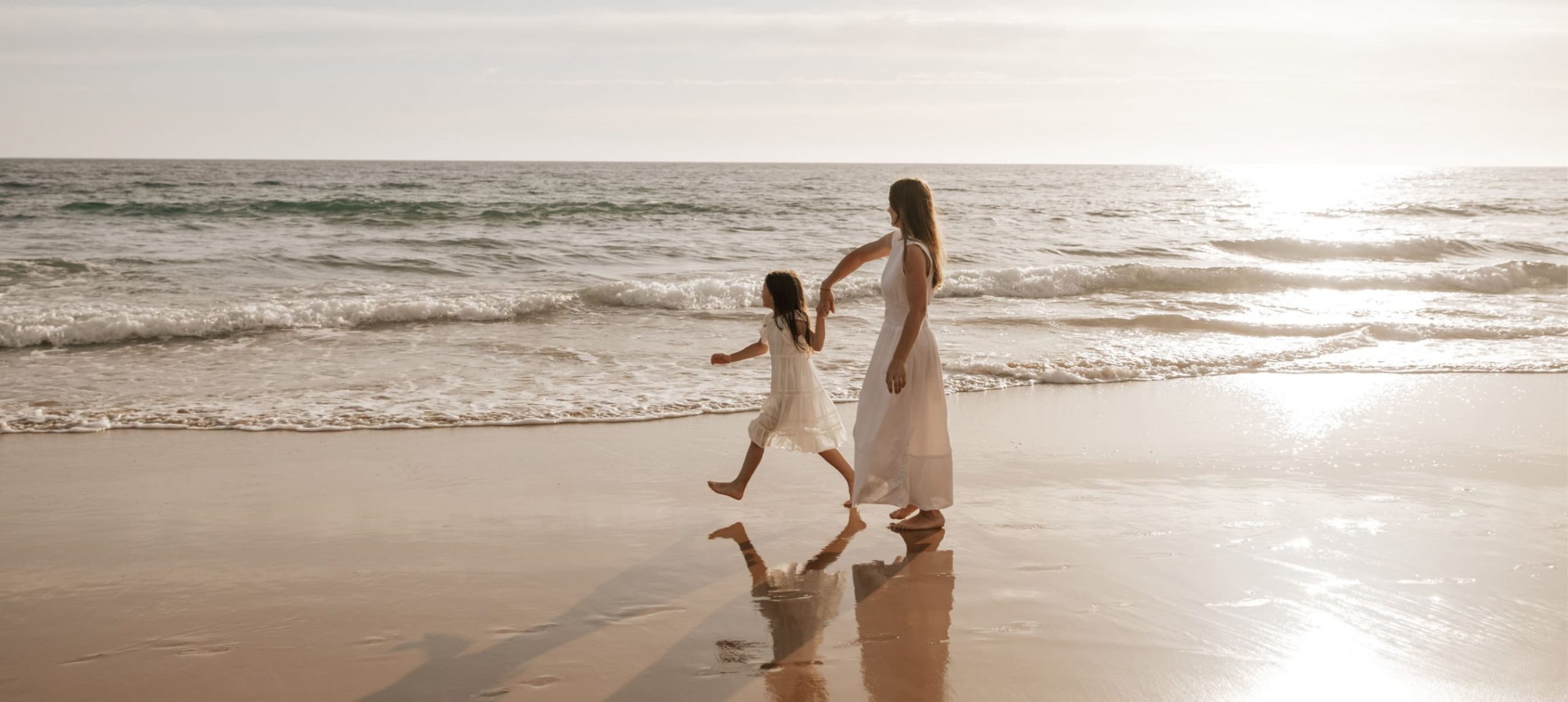 a woman and a child walking down a sandy beach